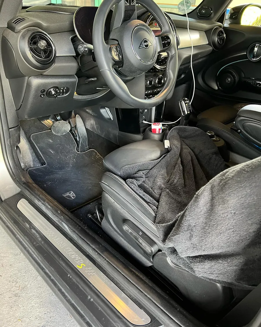 Fahrerbereich eines MINI Cooper S vor der Aufbereitung mit verschmutzten Fußmatten