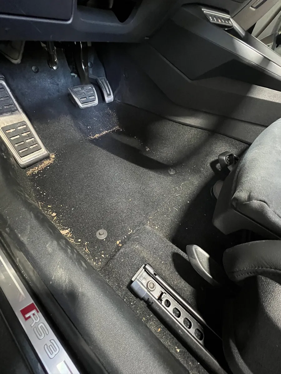 Verschmutzter Fußraum eines Audi RS3 vor der Innenraumreinigung