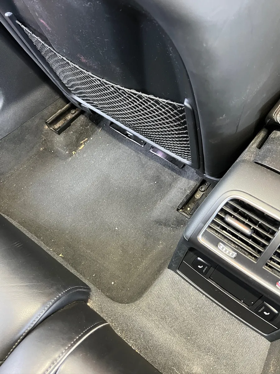 Fond-Fußraum eines Audi RS4 vor der Reinigung mit Krümeln und Schmutz