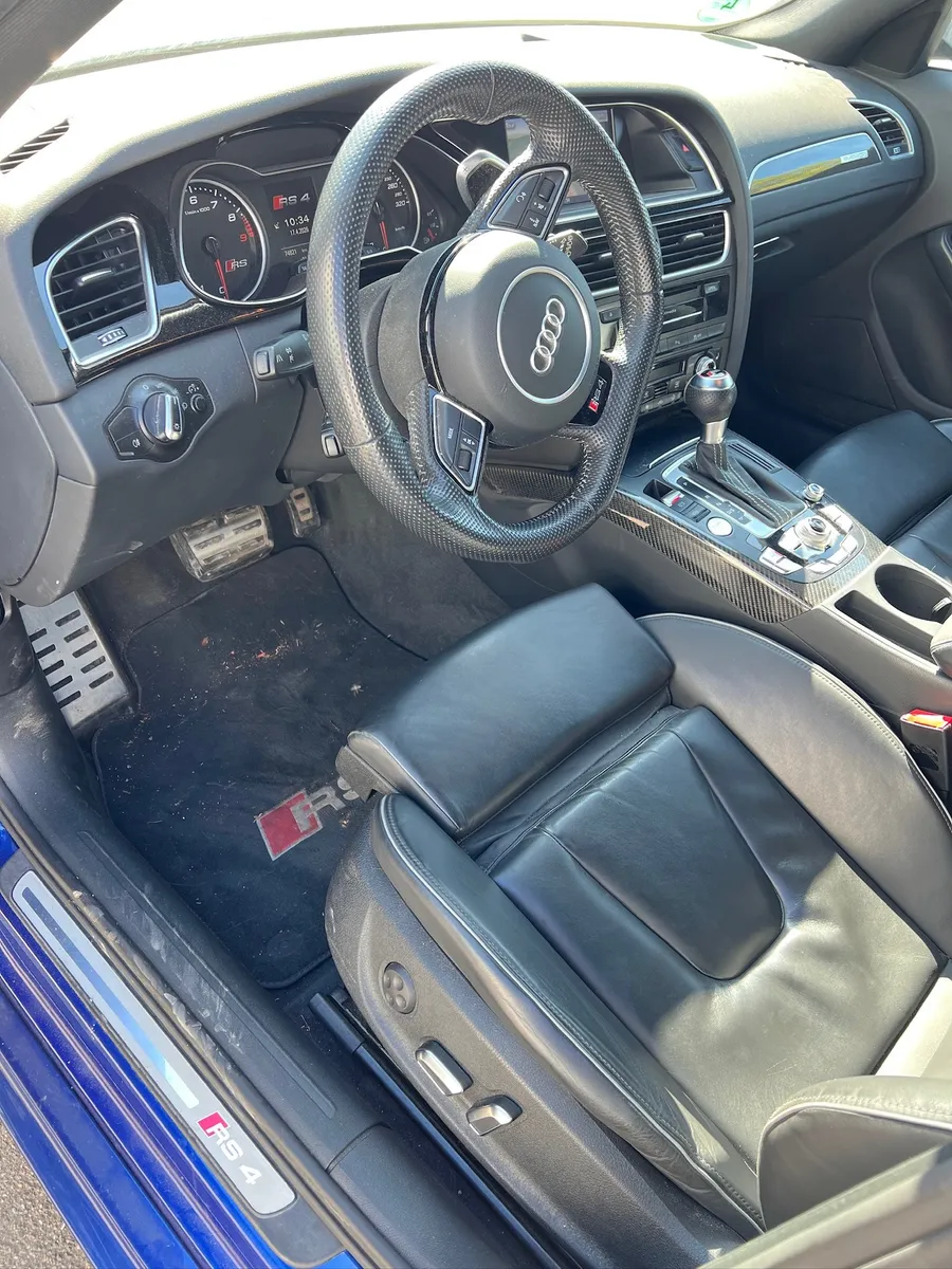 Fahrerbereich eines Audi RS4 vor der Innenraumreinigung mit Staub auf der Matte