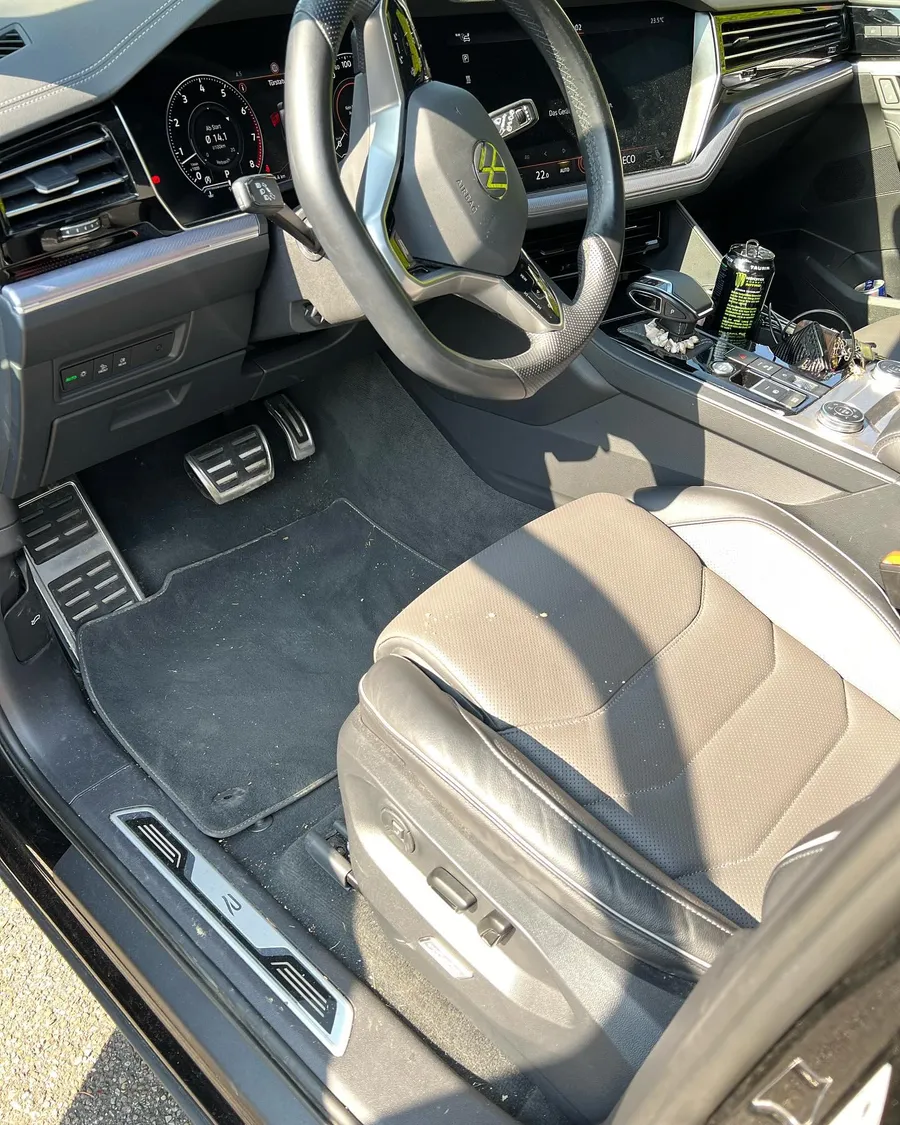 Cockpit eines VW Touareg vor der Aufbereitung mit verschmutzten Fußmatten