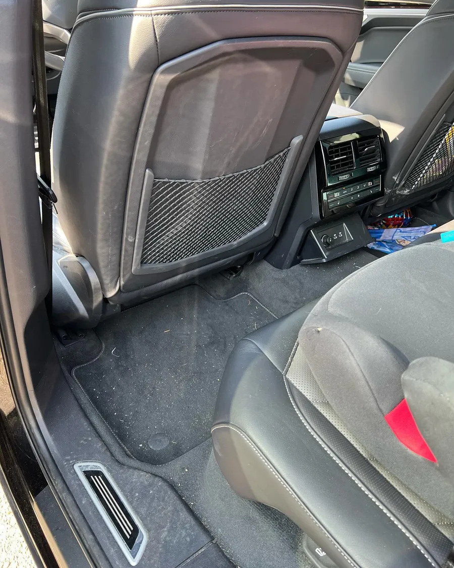 Fond eines VW Touareg vor der Reinigung mit Krümeln auf dem Teppich